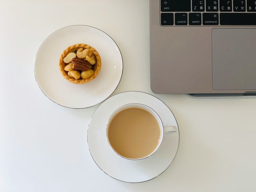 Top down view of a desk with laptop, notebook and coffee cup